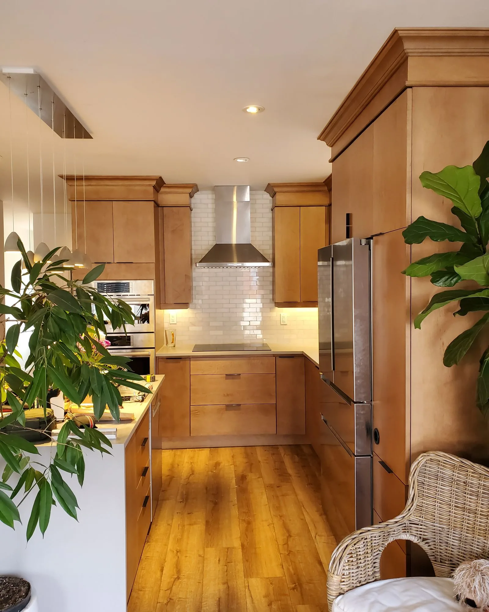 After: warm maple kitchen with a stainless hood, subway tile backsplash and hardwood floors