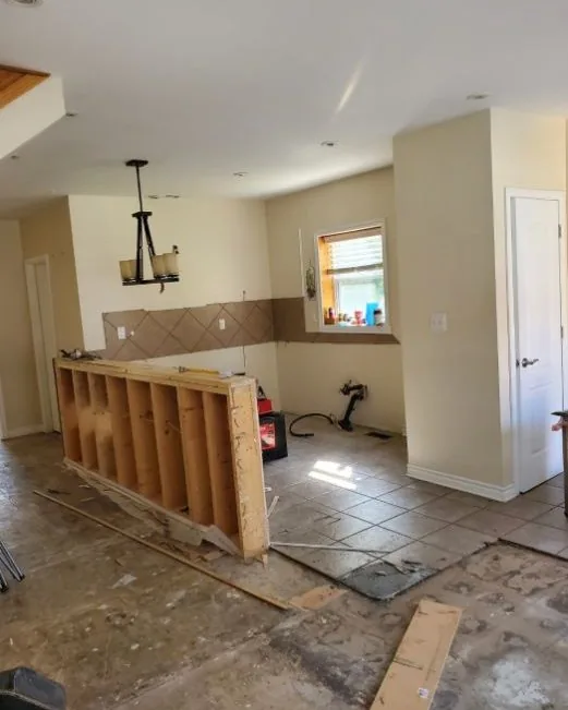 Before: a kitchen stripped back to the subfloor with the old peninsula framing exposed