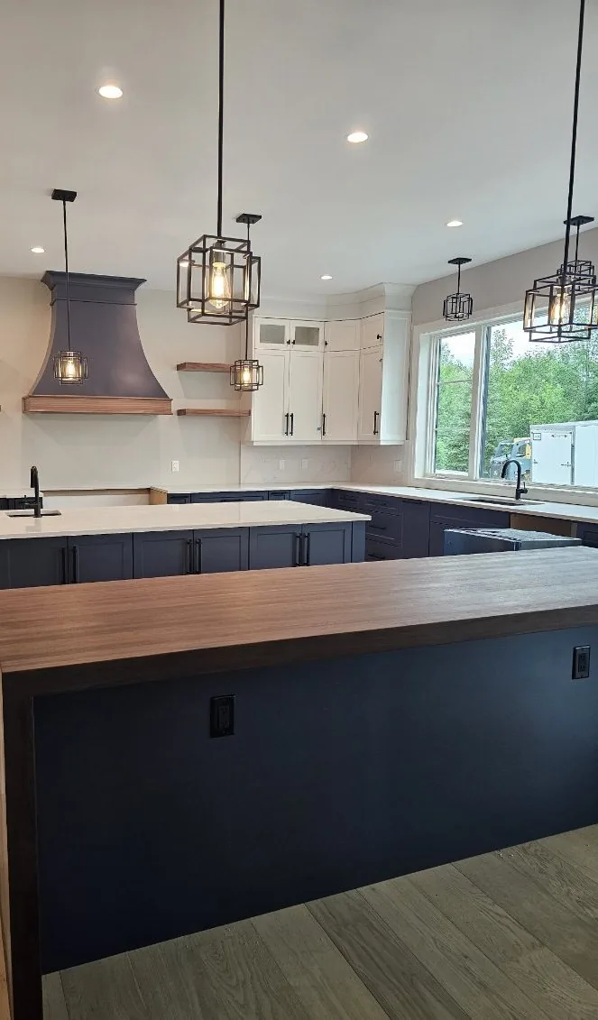 Kitchen with a navy blue island, butcher block walnut bar top and white perimeter cabinets