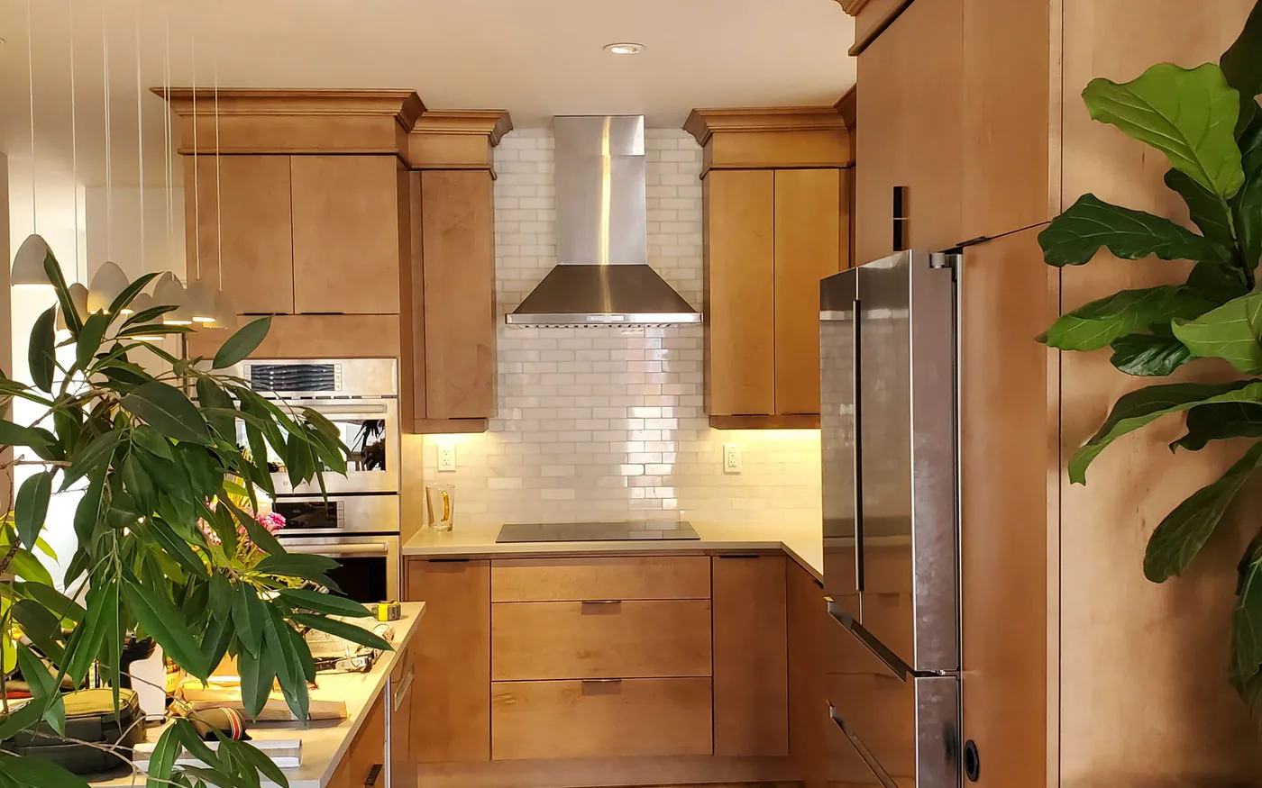 Warm maple kitchen with a stainless hood, subway tile backsplash and hardwood floors