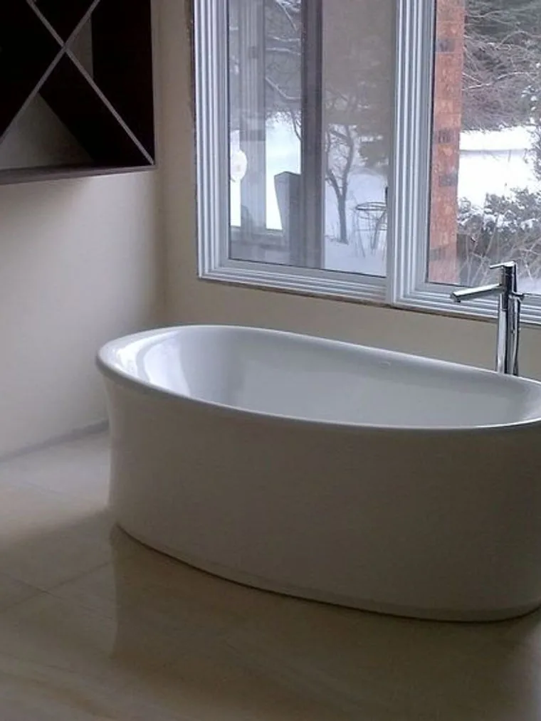 Freestanding soaker tub set in front of a window looking onto open country