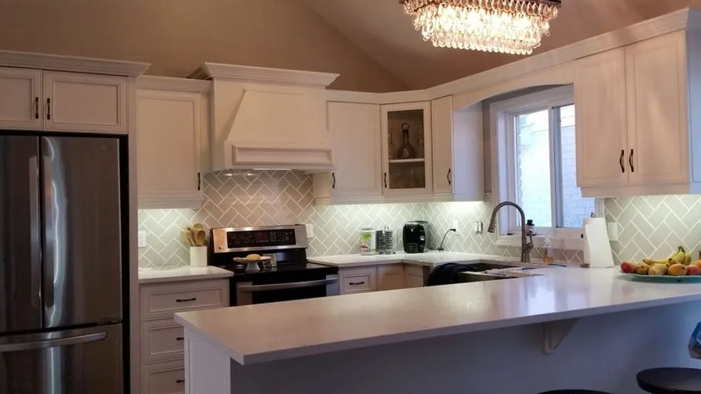 Shaker style painted condo kitchen in Guelph with a crystal chandelier and arched range hood